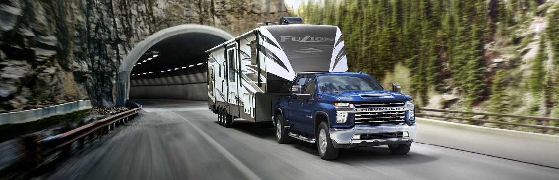 blue chevy silverado towing large camping trailer outside of a mountain tunnel