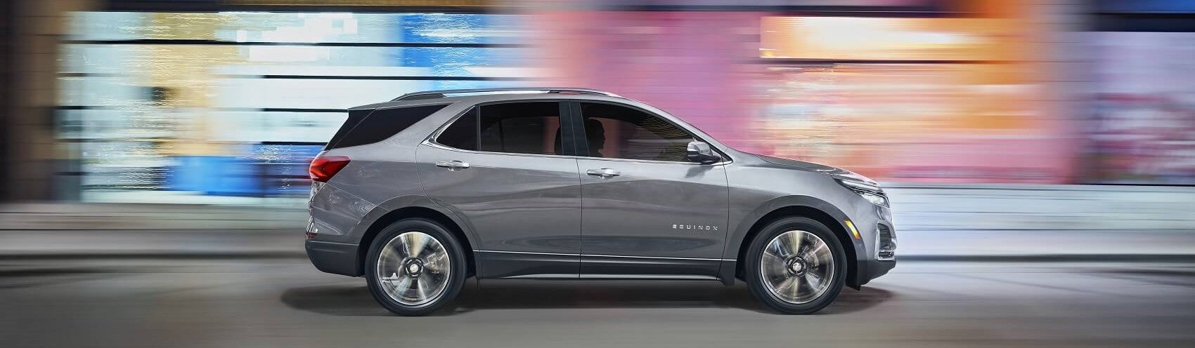 silver chevy equinox driving down street in front of colorful, blurred background
