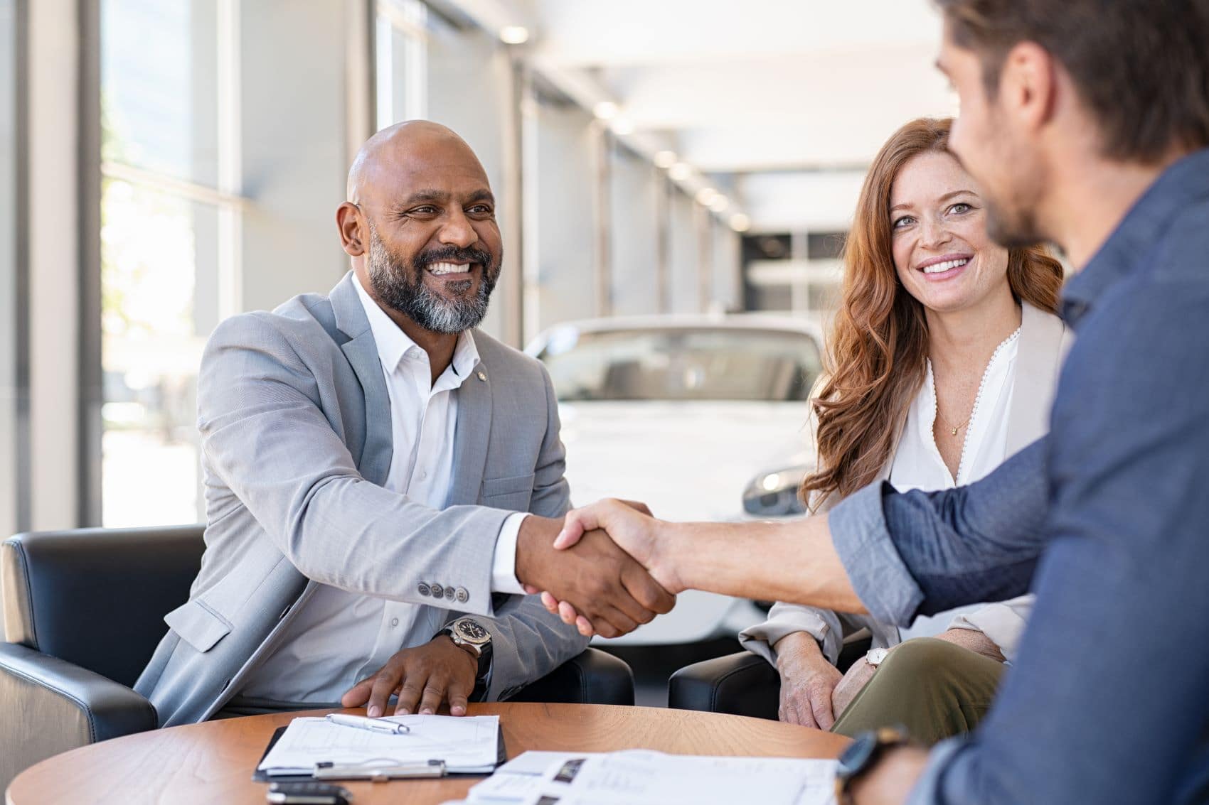 couple smiling and shaking hands with sales representative at feldman chevy highland finance center